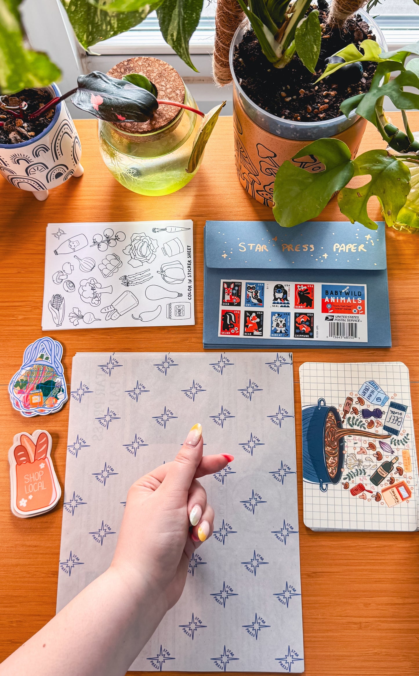 Hand holding a card on a desk with stationery items and plants